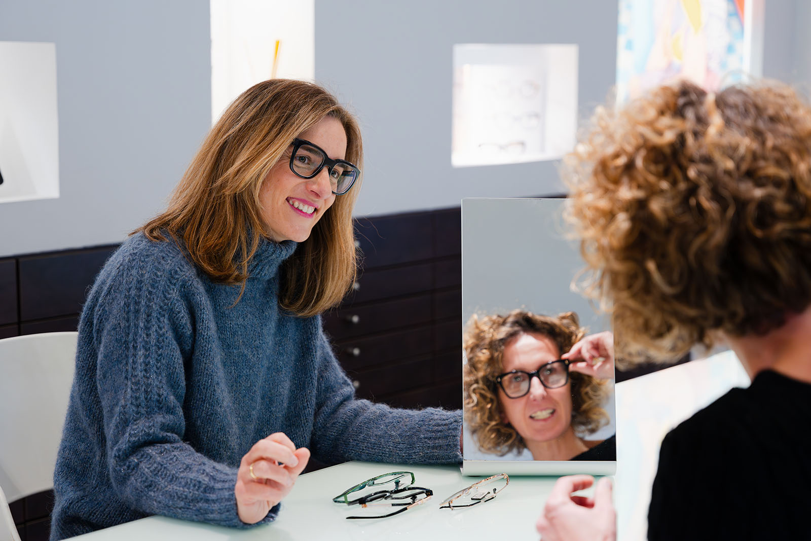 Augenoptikerin berät eine Kundin bei der Brillenanpassung
